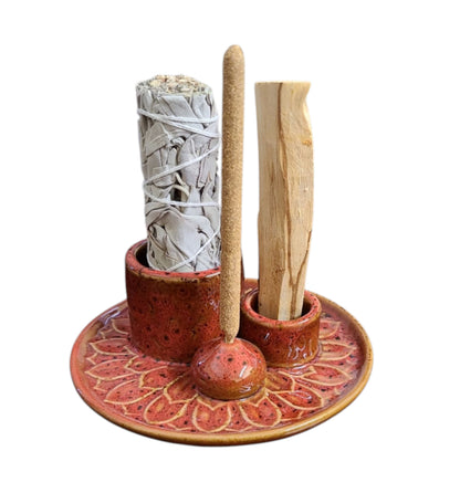 Ceramic holder with incense sticks and a sage bundle on a white background